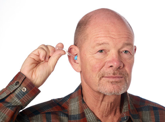 Middle aged male administers prescription ear drops using his right hand with no assistance